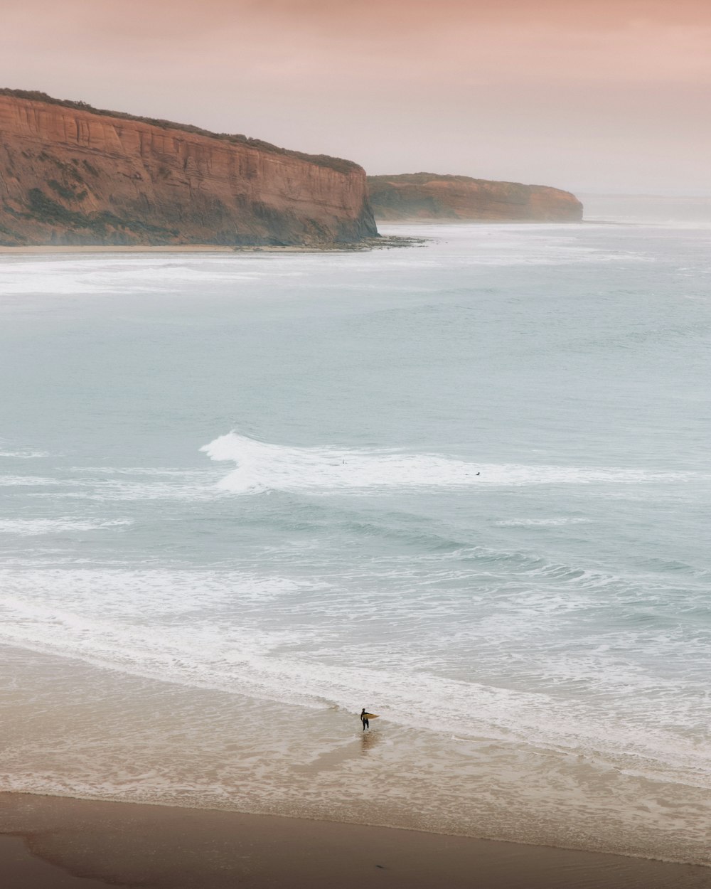 a person walking on a beach next to the ocean