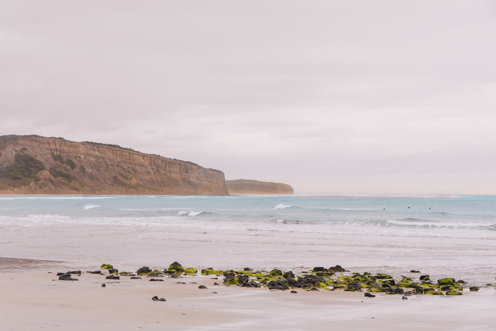 a sandy beach next to the ocean under a cloudy sky