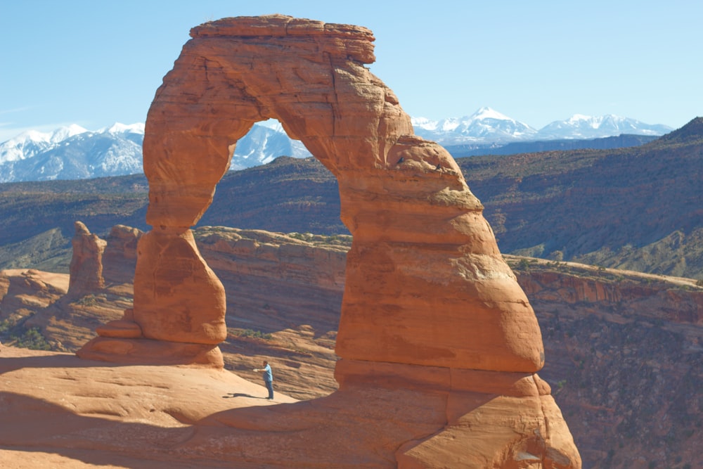 a person standing in front of a large rock formation