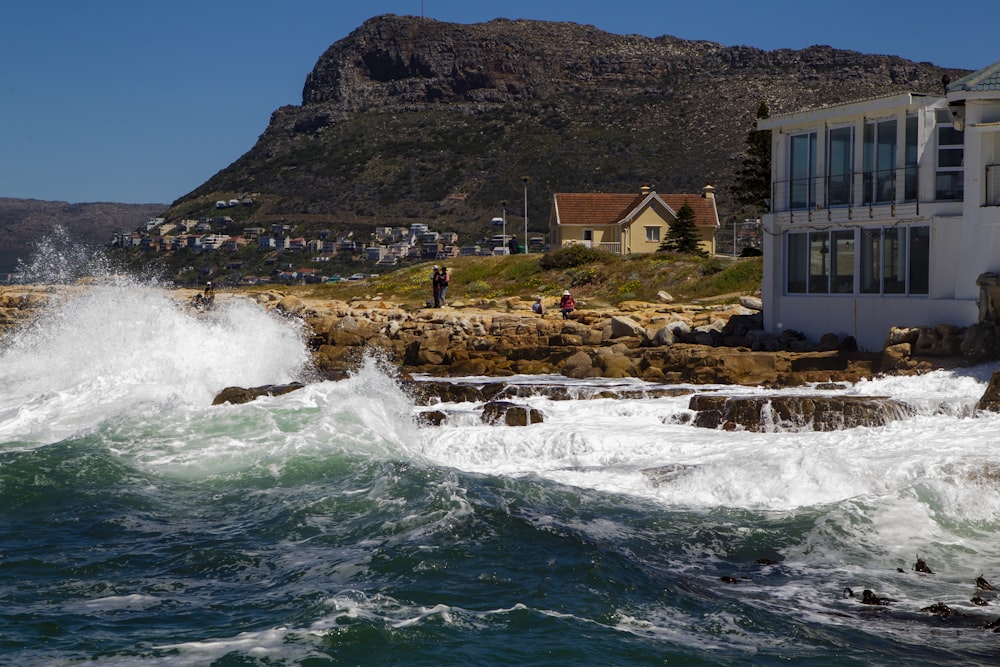 a house on the shore with waves crashing in front of it