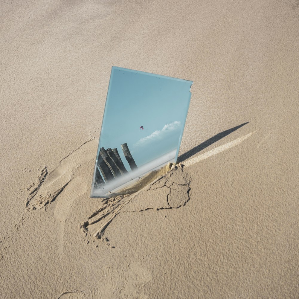 a reflection of a building in a mirror on a beach