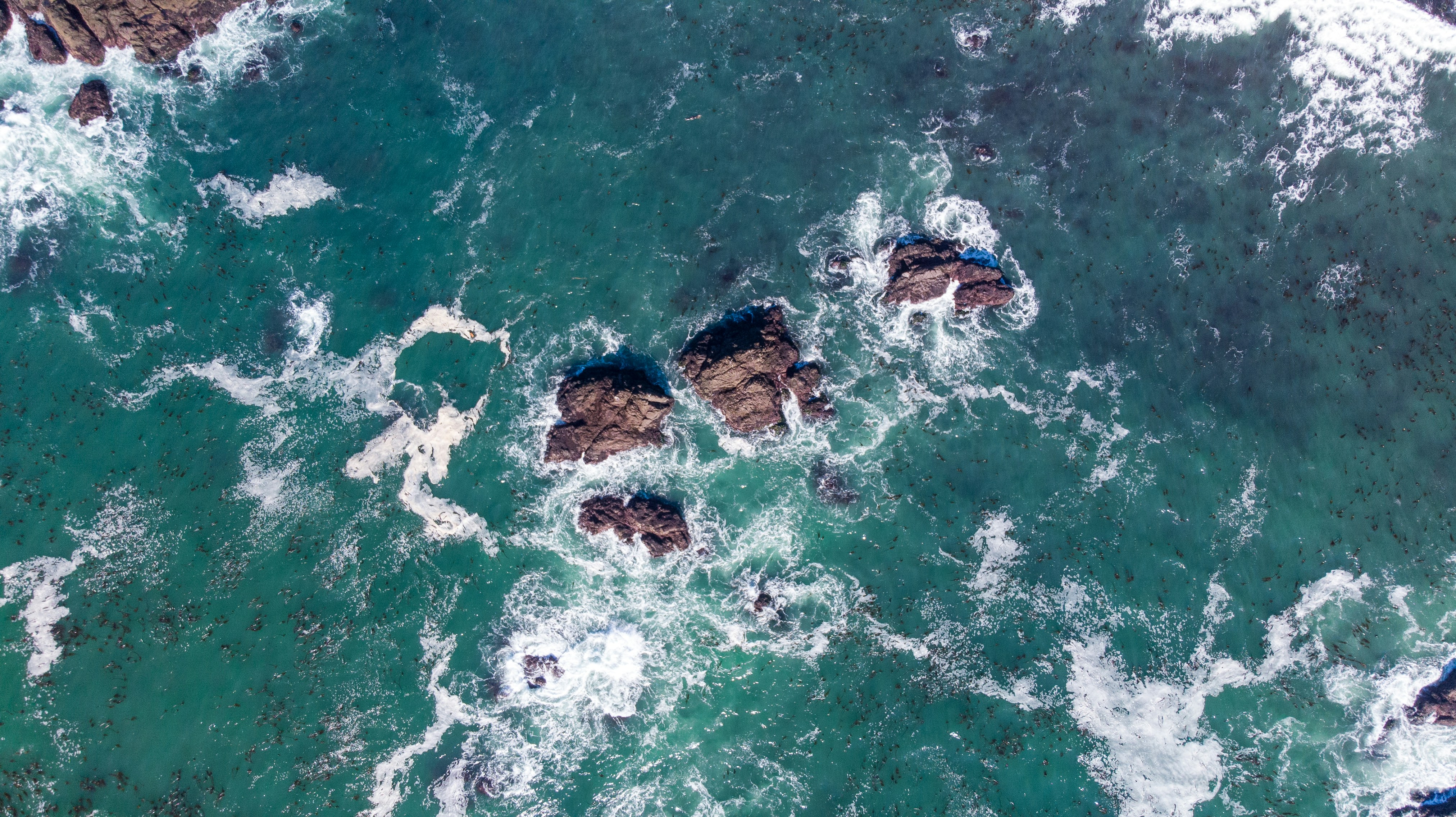 an aerial view of the ocean and rocks