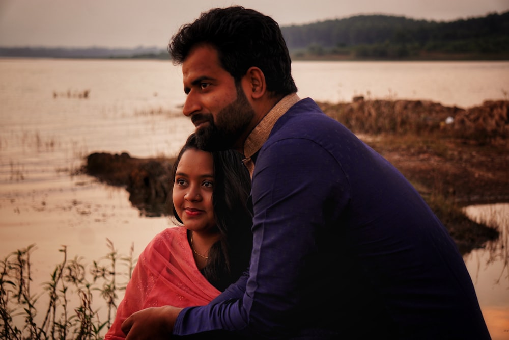 a man sitting next to a woman near a body of water