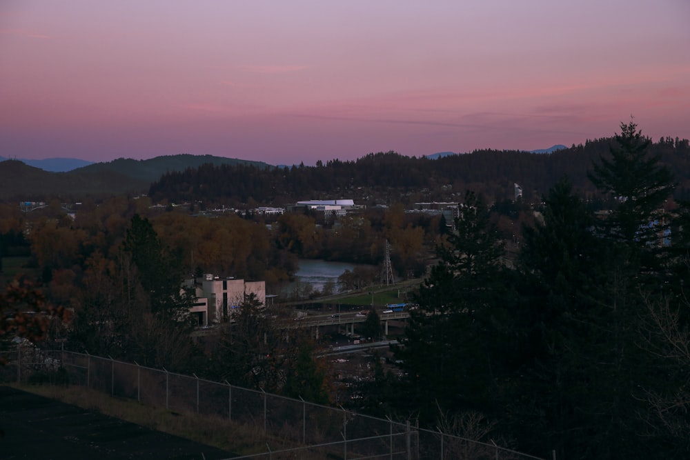 a sunset view of a city with mountains in the background