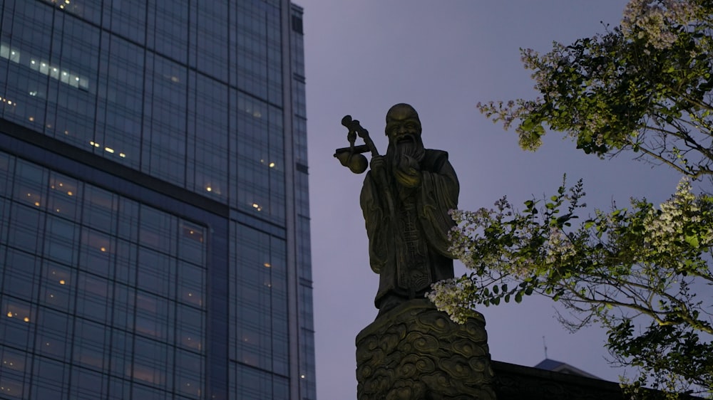 a statue of a man holding a bird next to a tall building