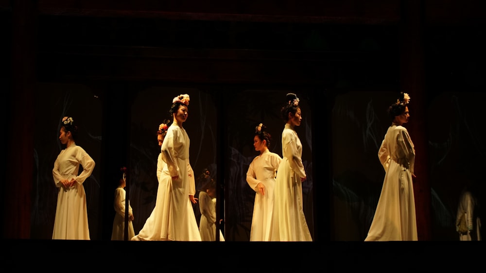 a group of women in white dresses on stage