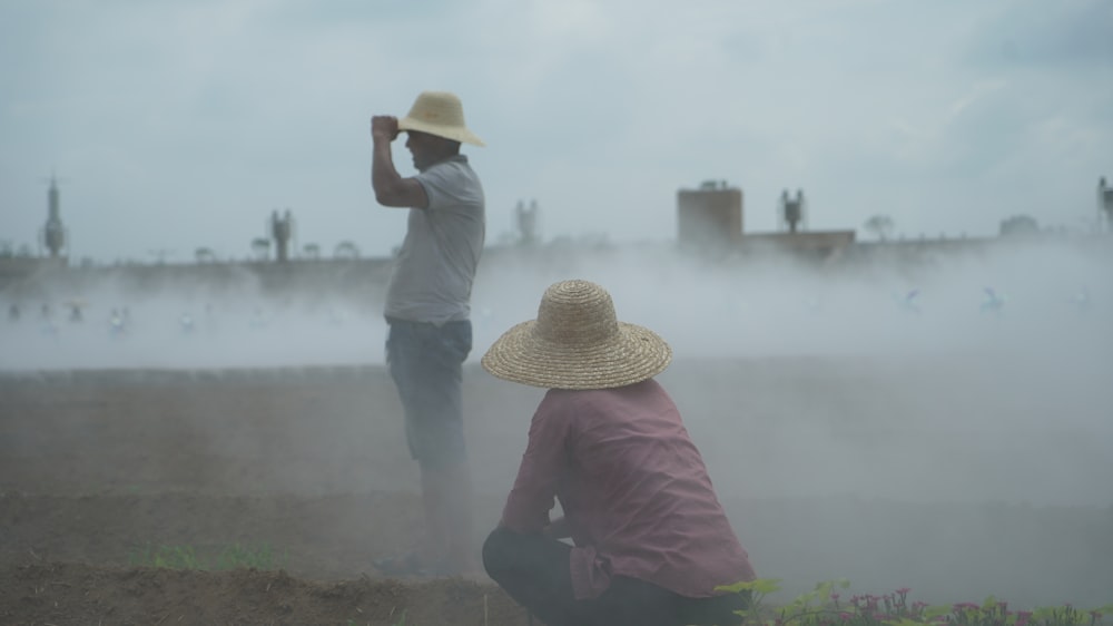 a man kneeling down next to another man in a field