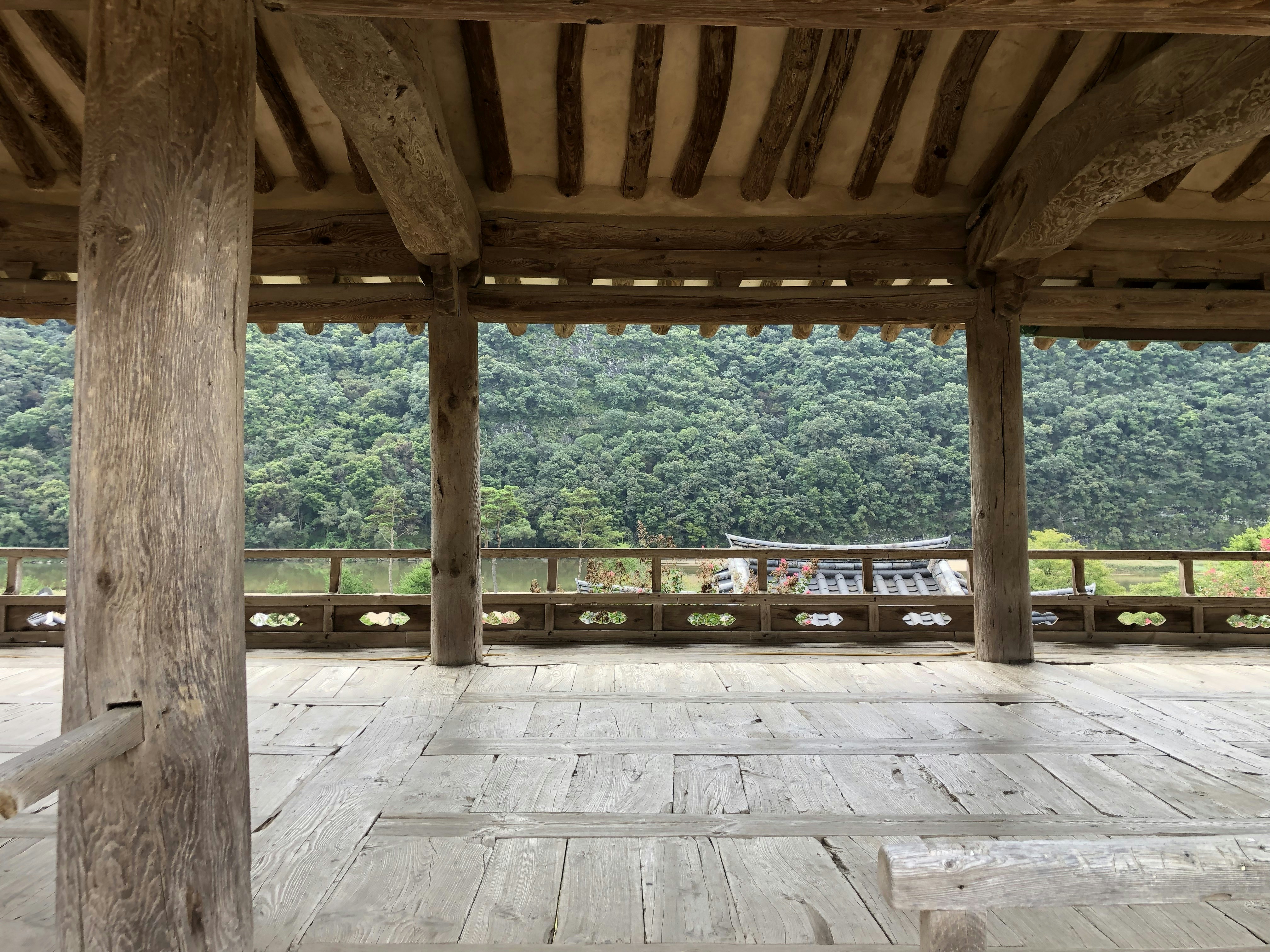 a large wooden structure with columns in front of a forest