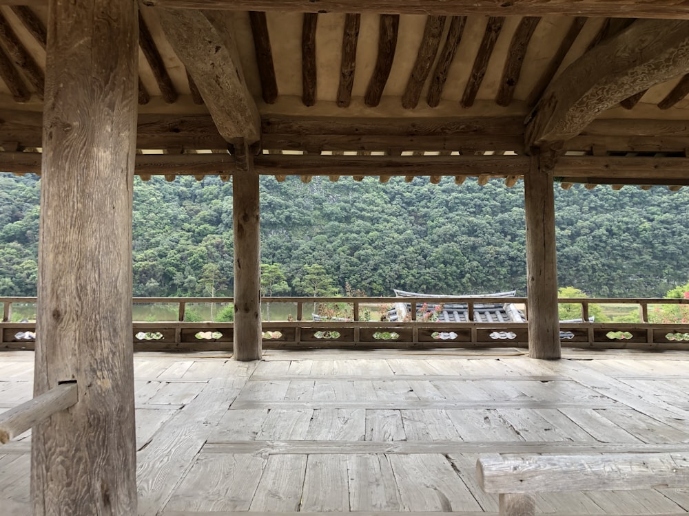 a large wooden structure with columns in front of a forest