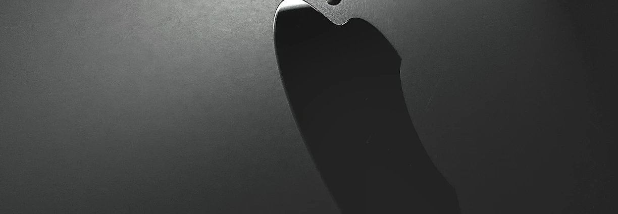 A close-up view of a metallic surface with a prominent, illuminated logo. The lighting creates a sleek and modern aesthetic with the logo casting a subtle shadow.