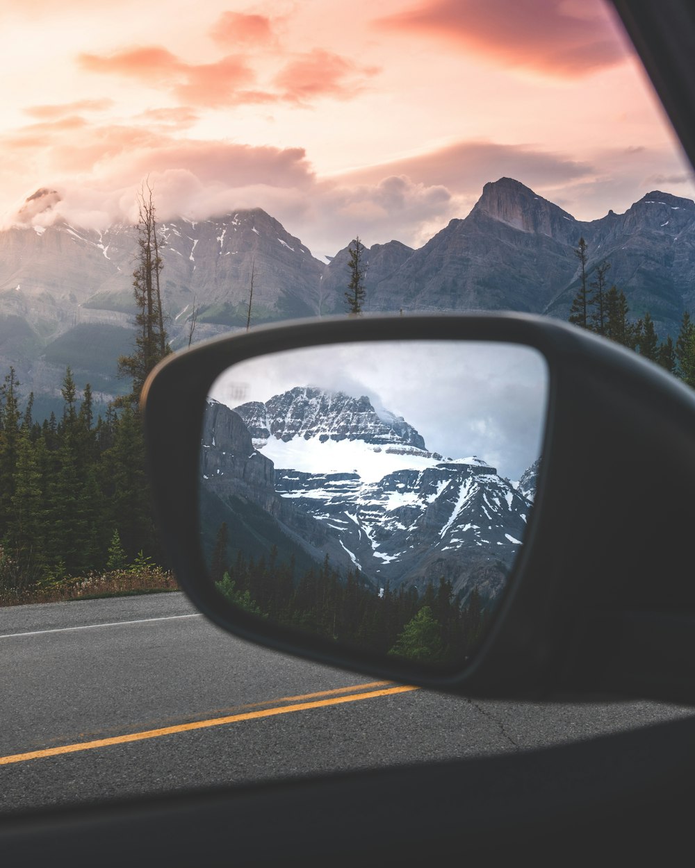 a car's side view mirror with a mountain in the background