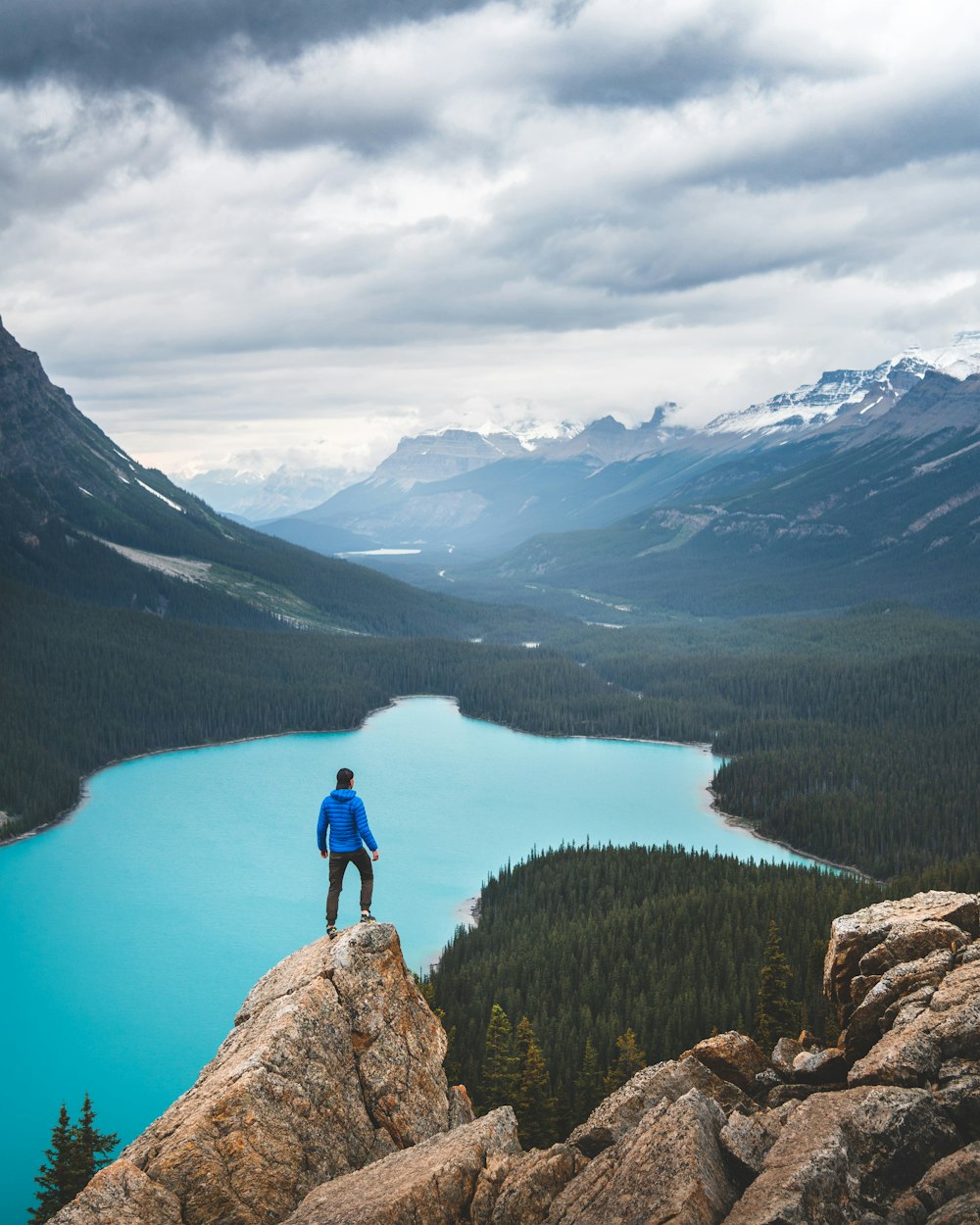 a man standing on top of a rock next to a lake