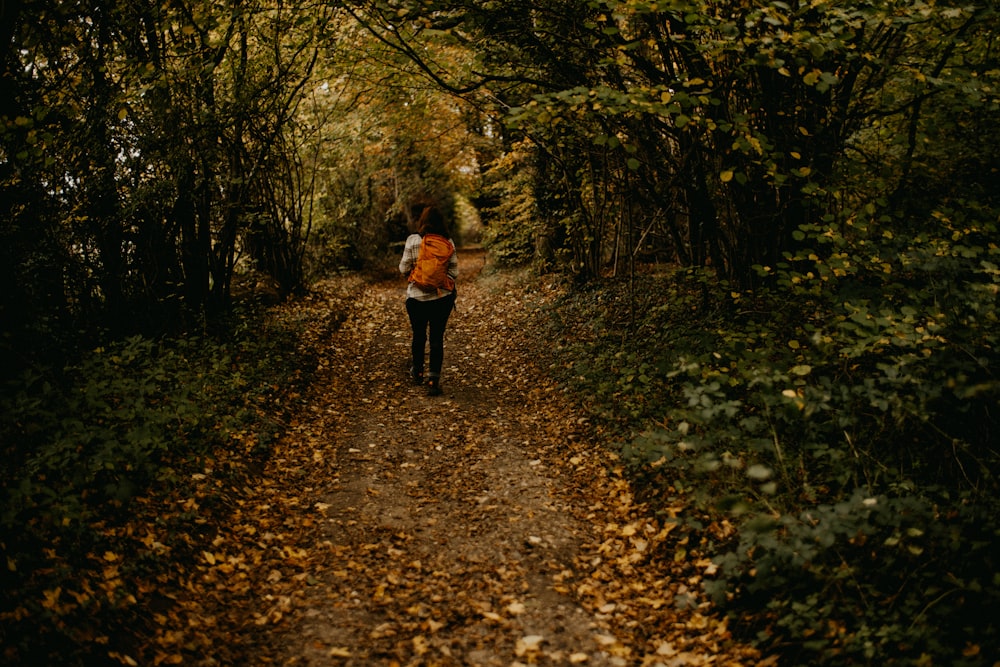 a woman is walking down a path in the woods