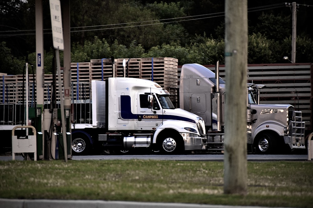 a semi truck driving down a street next to a wooden fence