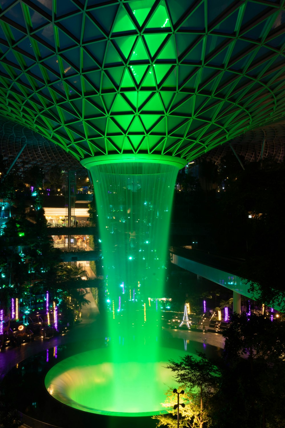 a green fountain lit up at night in a city