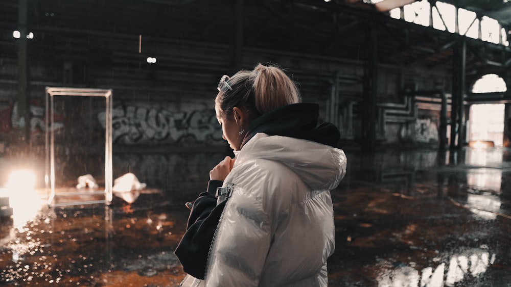 a woman in a white jacket standing in a building