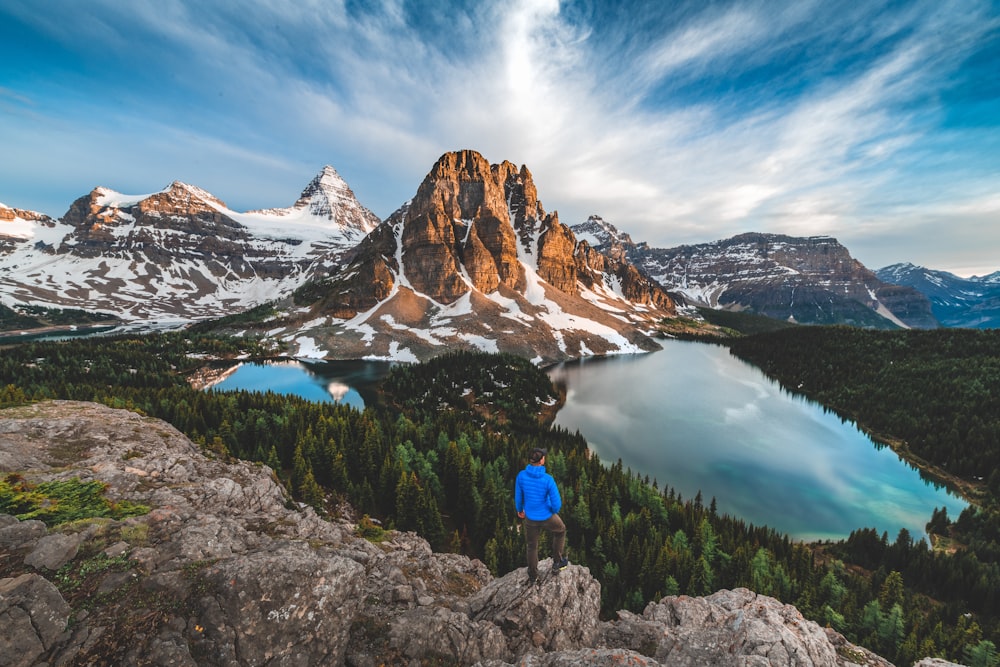 a man standing on top of a mountain next to a lake