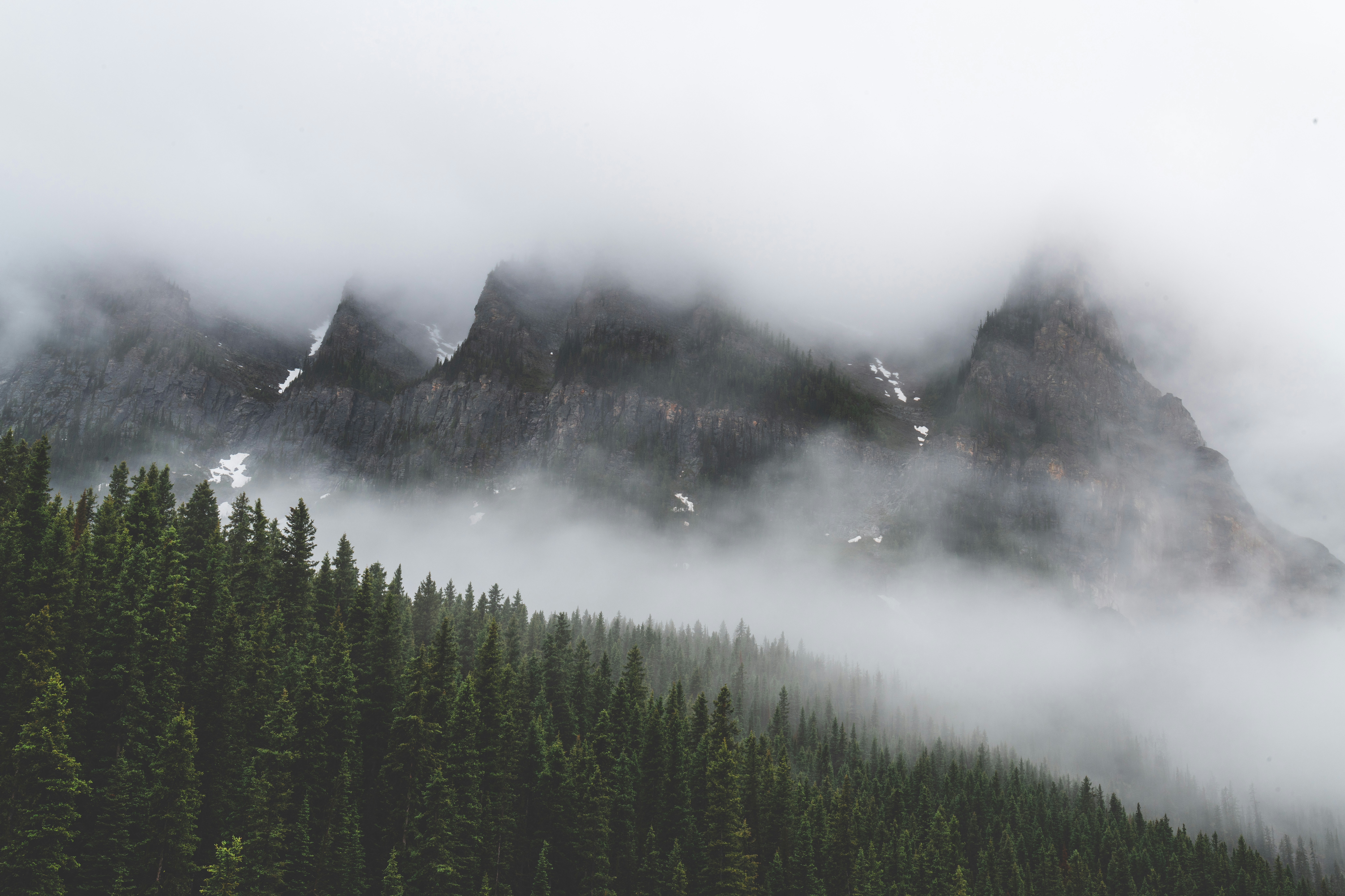 a mountain covered in fog and low lying clouds, Misty morning at lake Louise in Caada