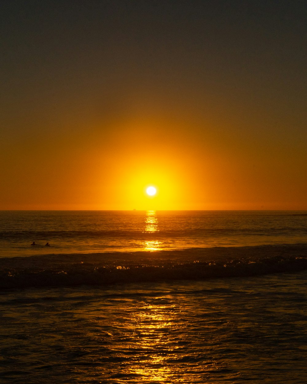 the sun is setting over the ocean on the beach