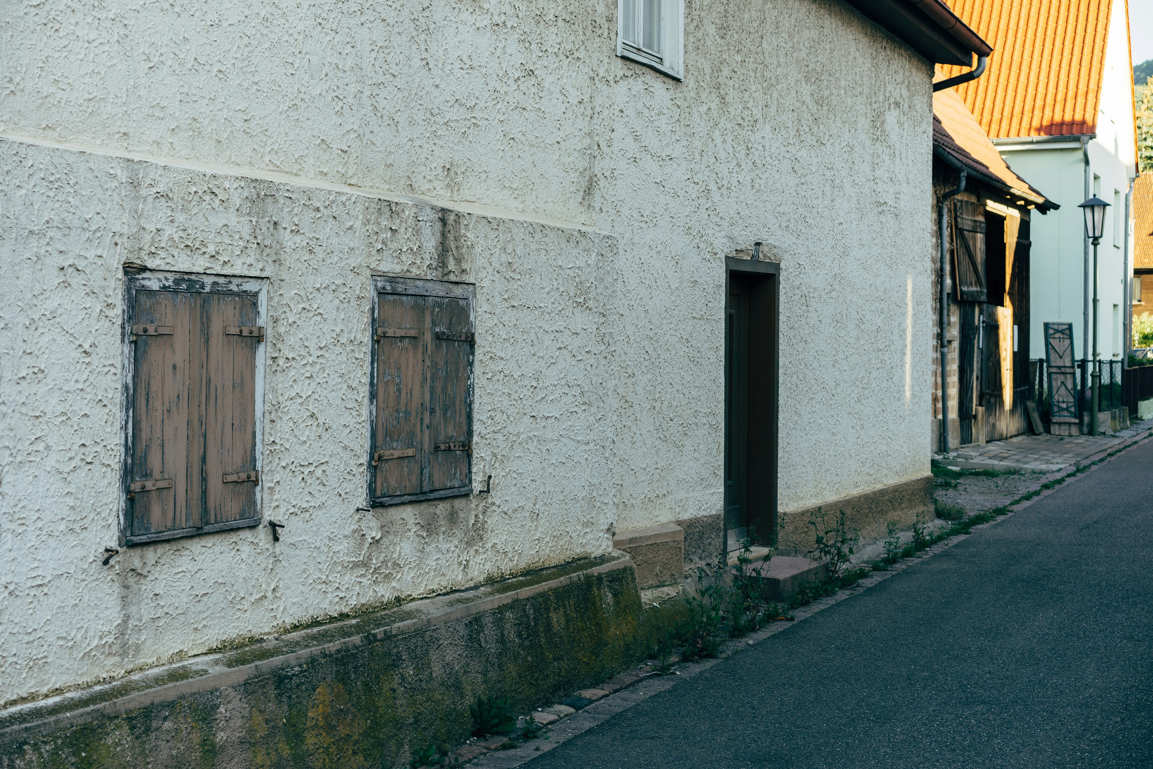 a narrow street with a white building and a red fire hydrant