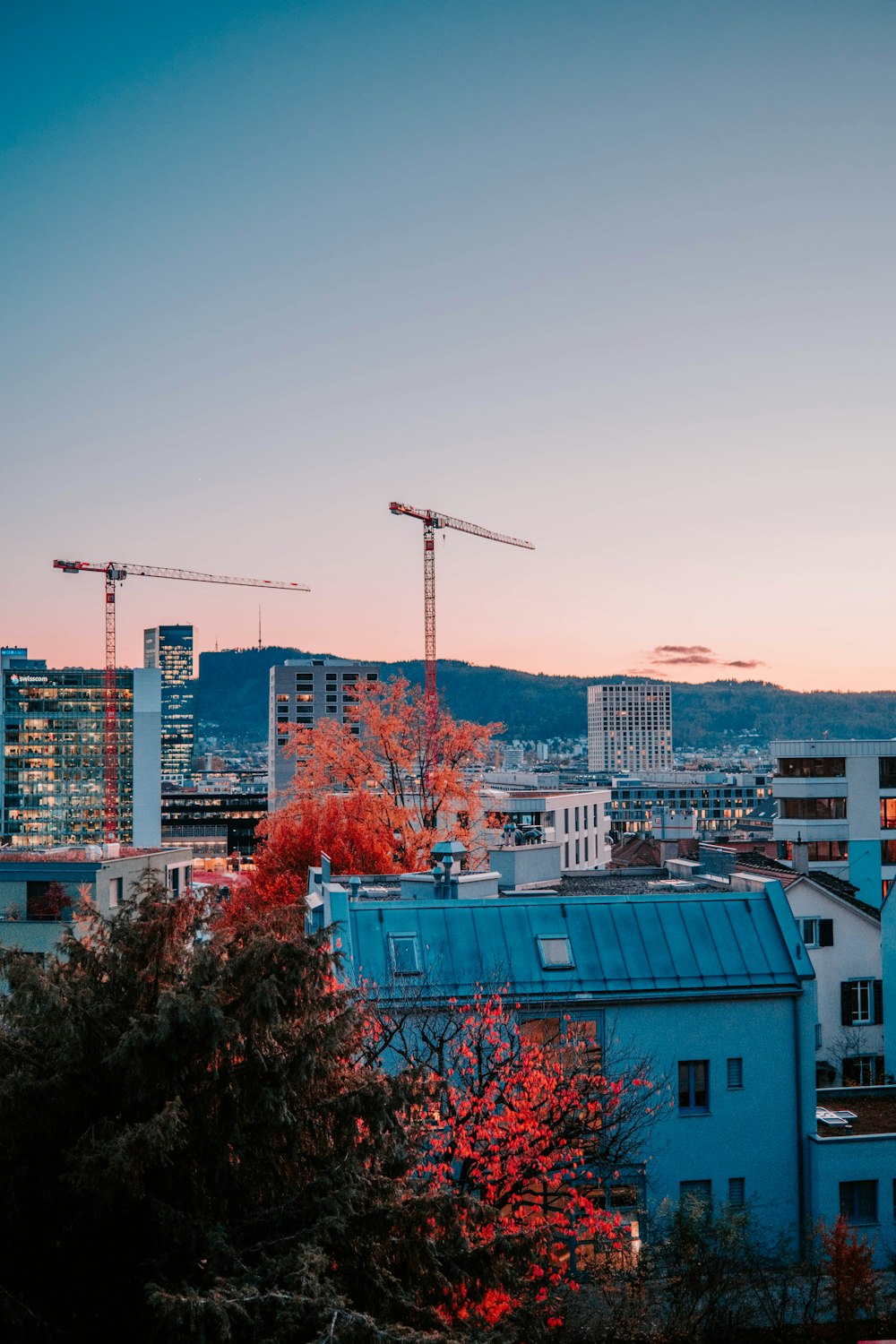 a view of a city with cranes in the background