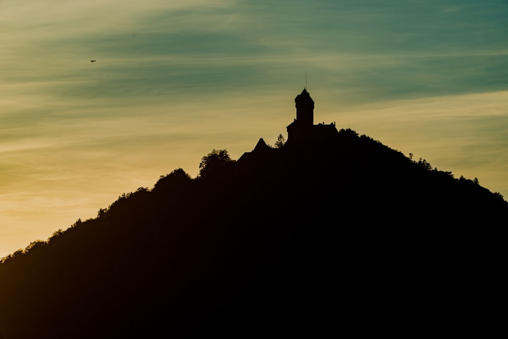 a clock tower on top of a hill at sunset