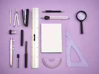 a variety of office supplies laid out on a purple surface