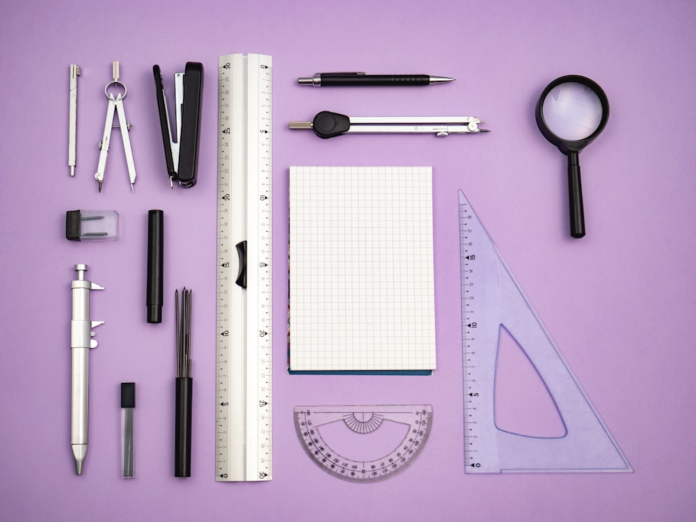 a variety of office supplies laid out on a purple surface
