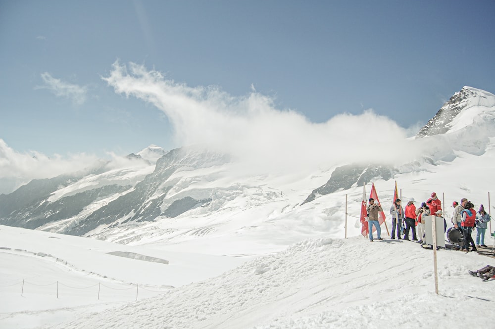 Un grupo de personas de pie en la cima de una ladera cubierta de nieve