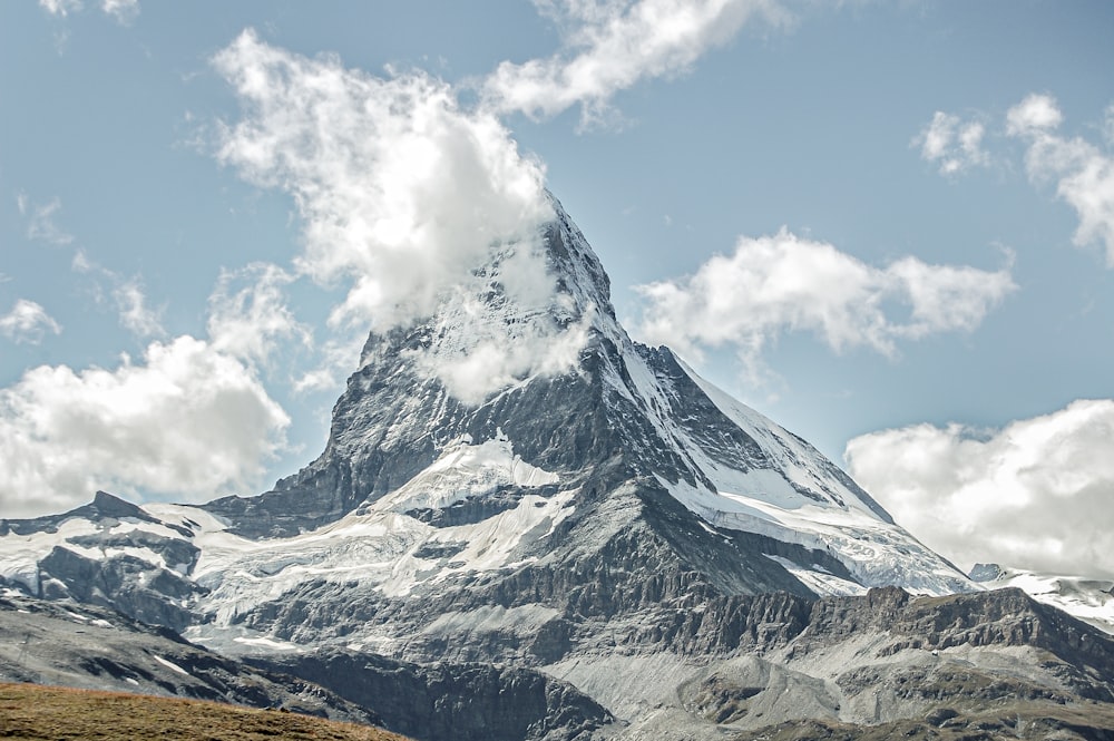 a large snow covered mountain towering over a green field