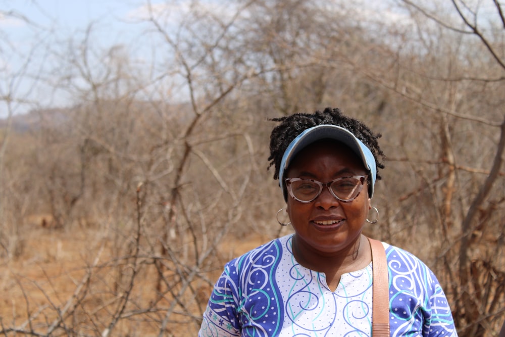 a woman standing in a field with trees in the background