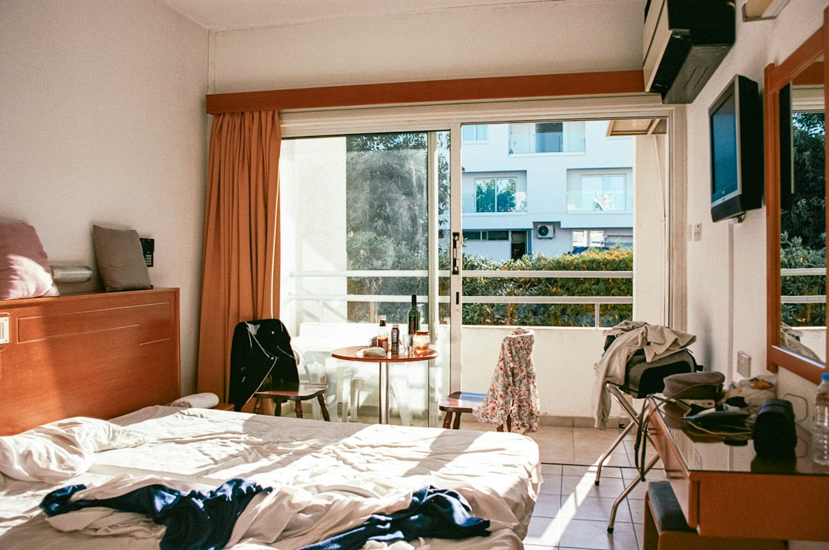 A hotel room with a neatly made bed and a large window, ideal for youth sports tournament travel accommodations.