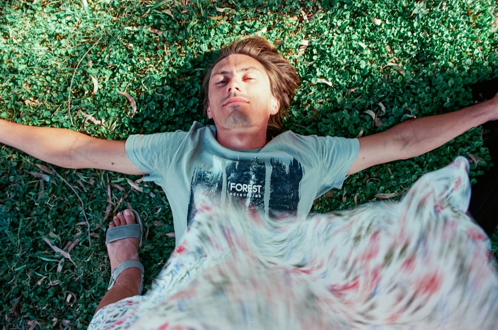 a man laying in the grass with his arms outstretched