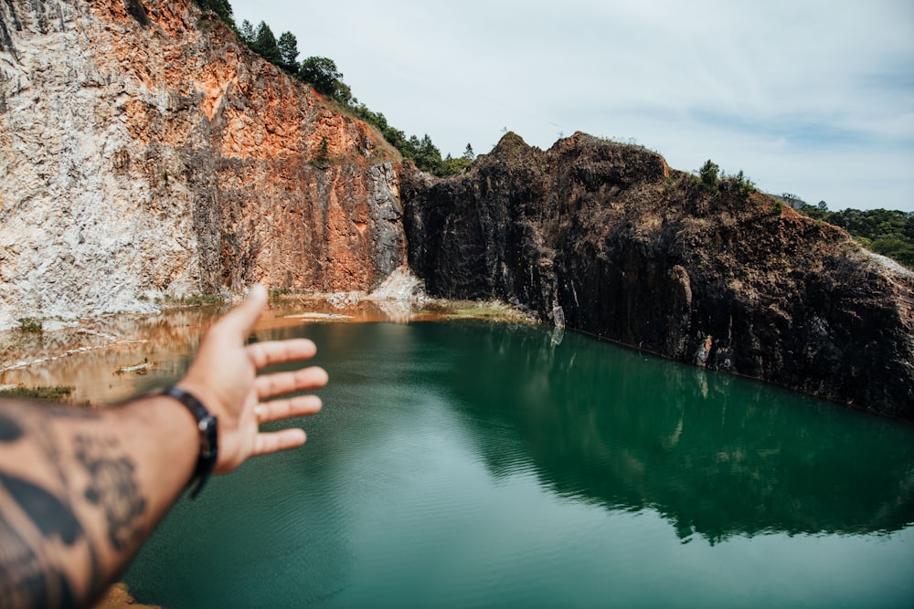 a hand reaching out towards a large body of water