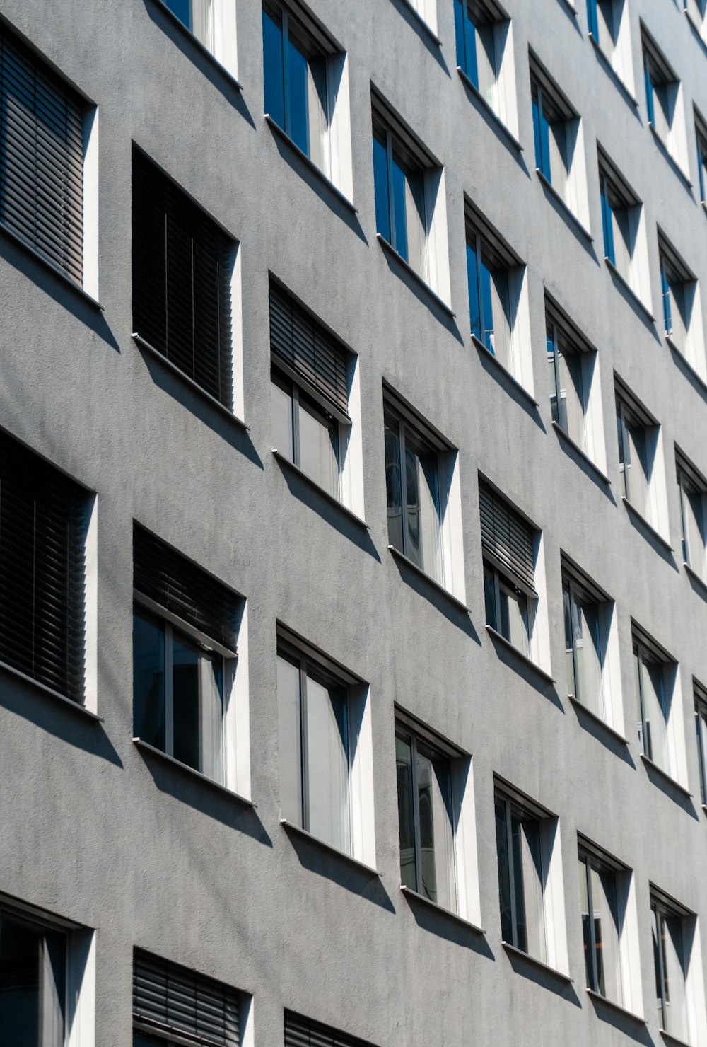 a grey building with many windows and shutters