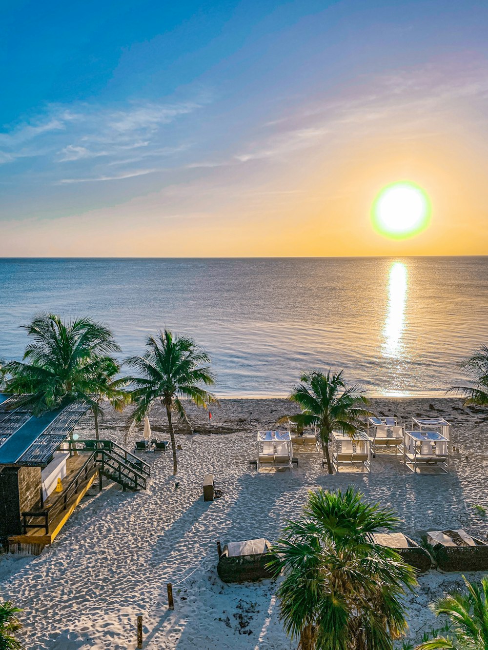 the sun is setting over a beach with palm trees