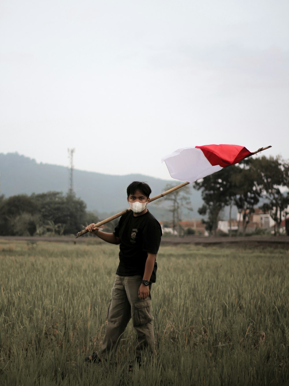 a man holding a red and white umbrella in a field