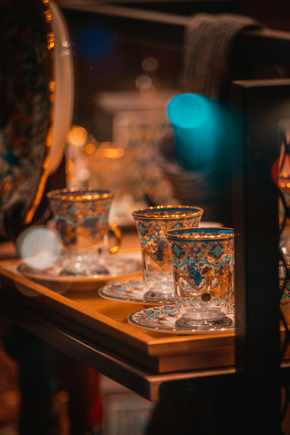 a wooden table topped with glass cups and saucers