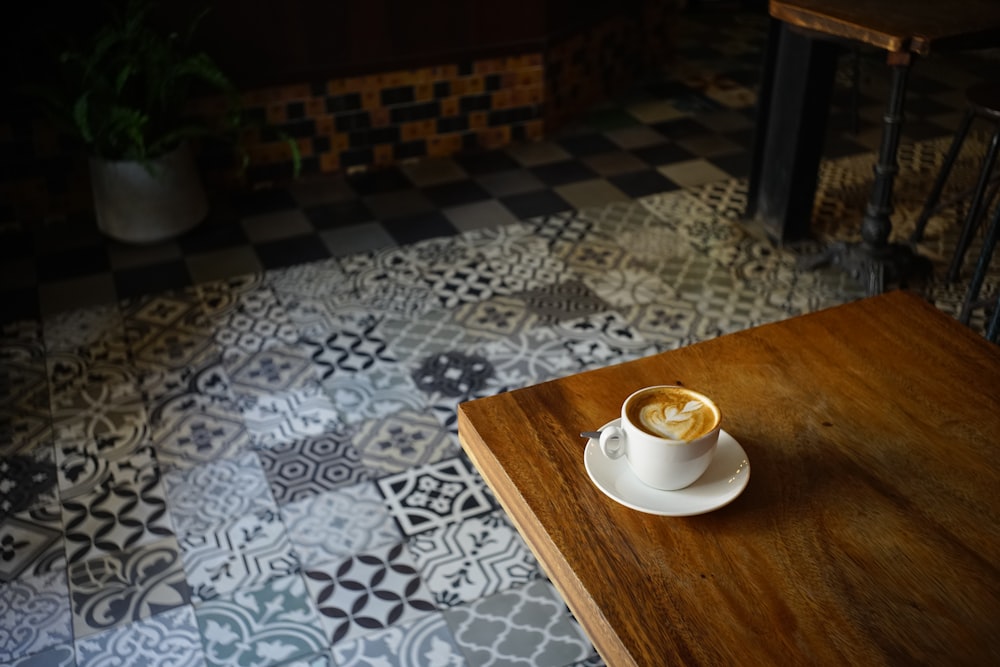 a cup of coffee sitting on top of a wooden table