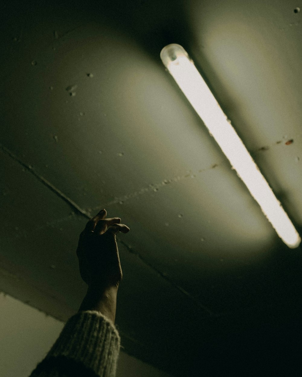 a person reaching up to a light in a dark room