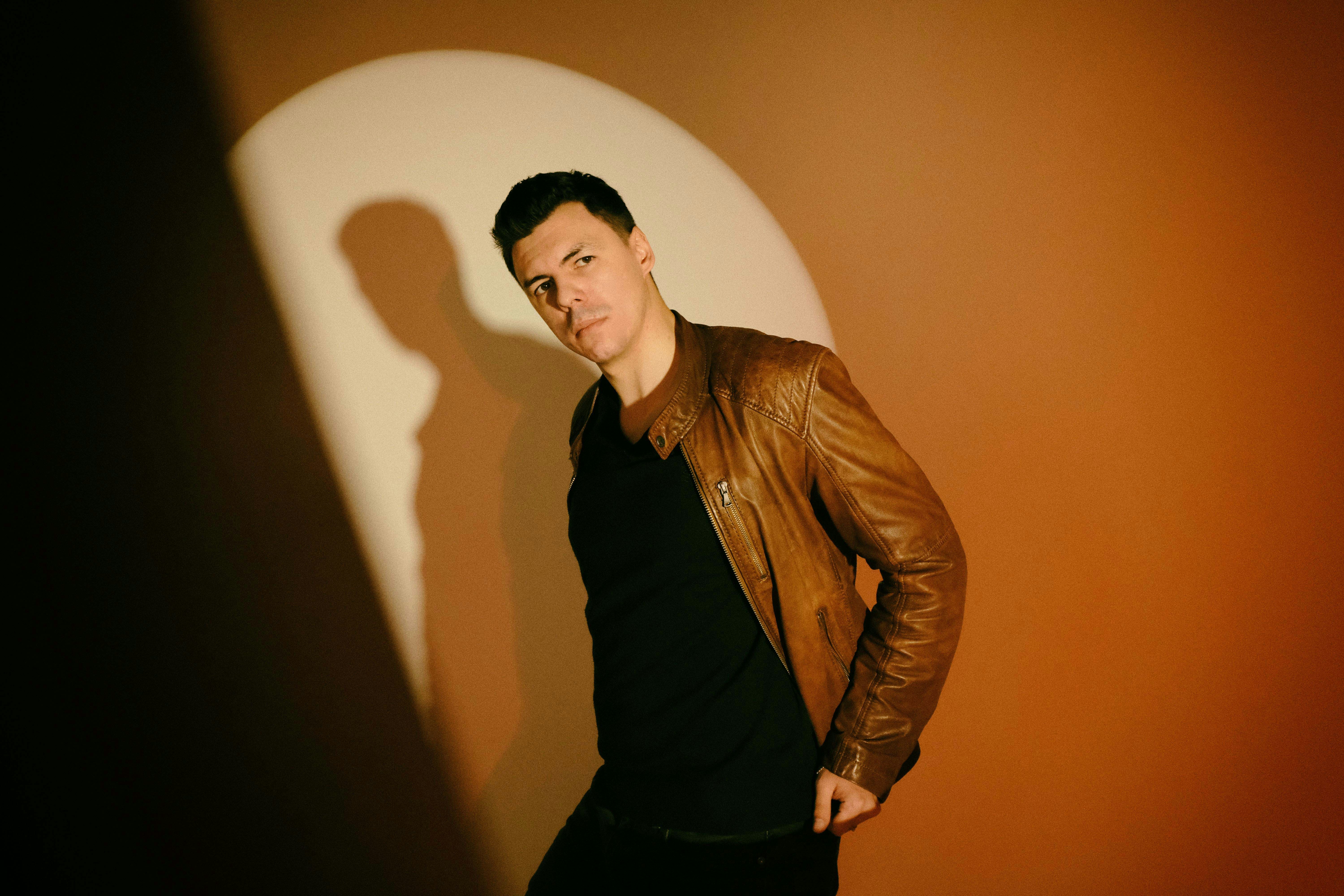 a man standing in front of a wall with a shadow on it