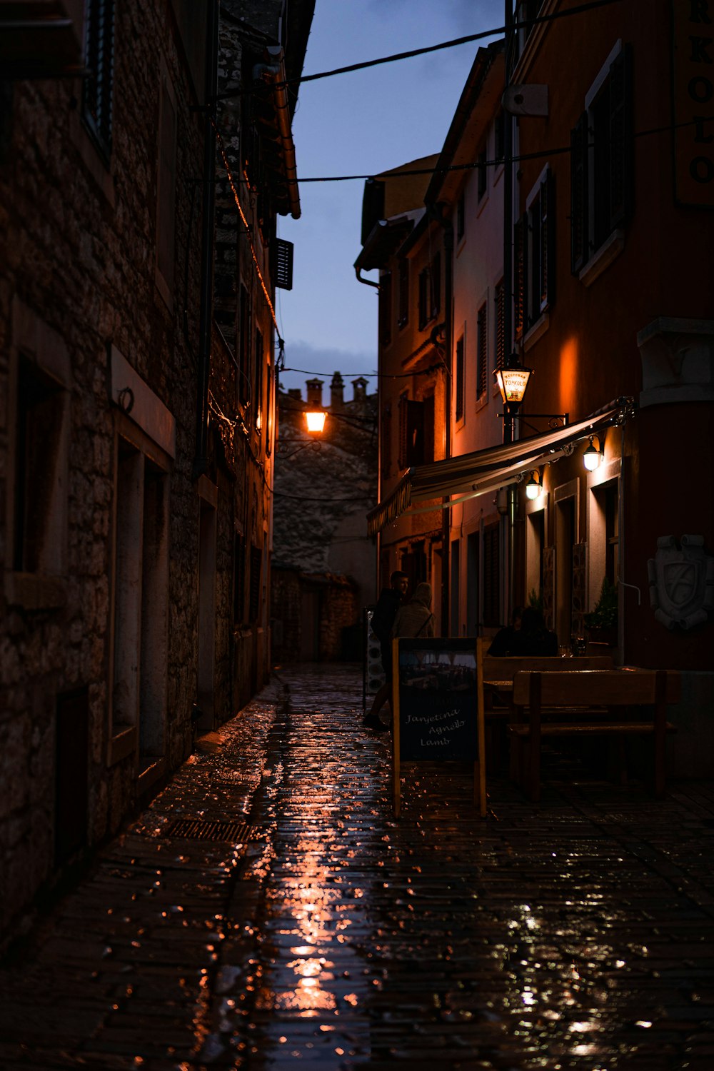 a dark alley way with a bench and street lights