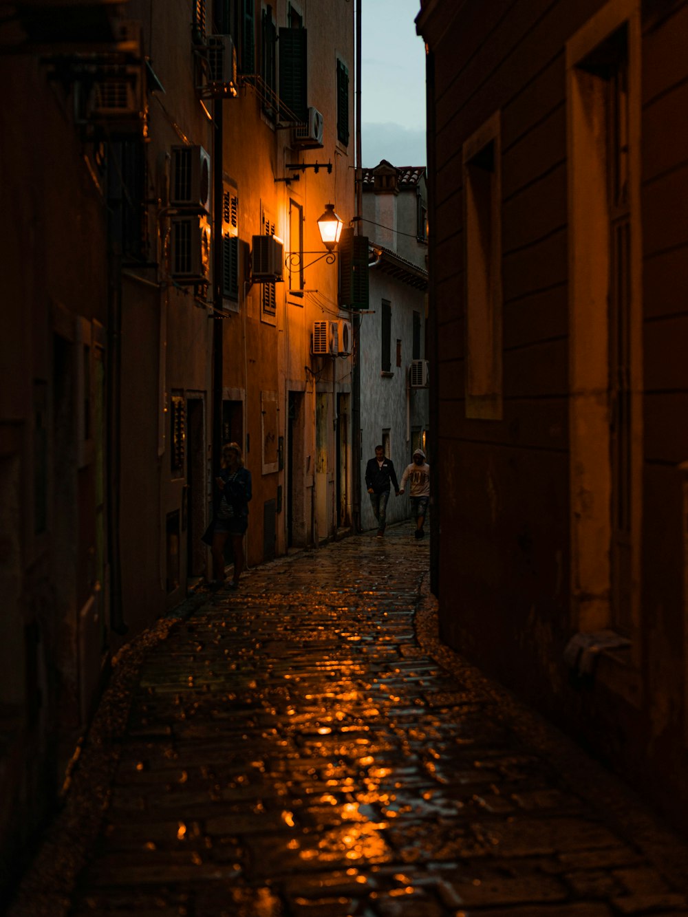 a narrow alley way with people walking down it at night