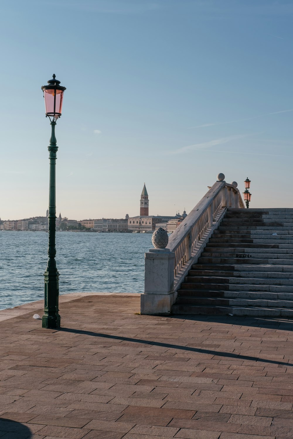 a lamp post sitting on the side of a road next to a body of water