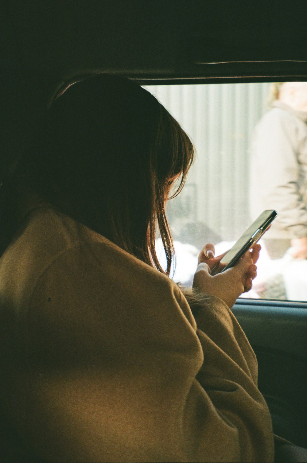 a woman sitting in a car holding a cell phone