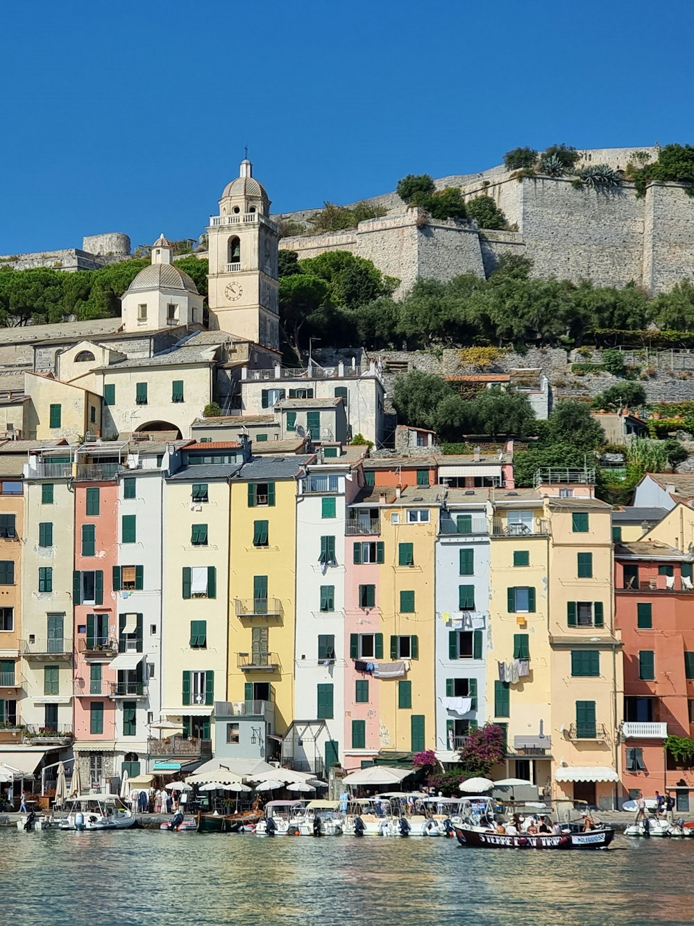 a group of buildings sitting on top of a hill next to a body of water