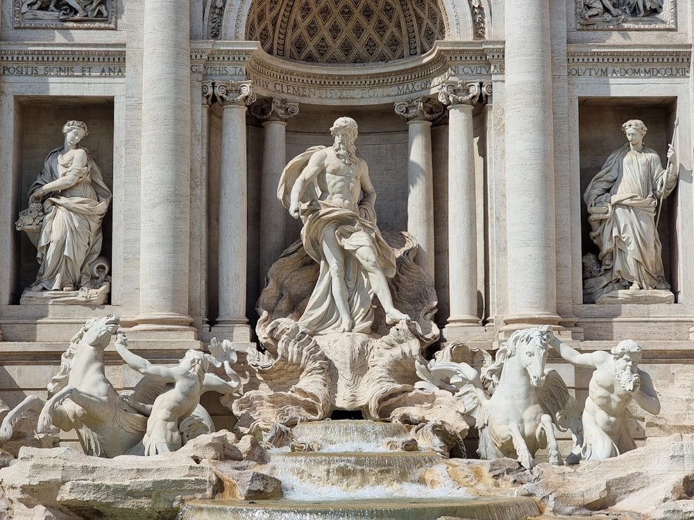 a fountain with statues surrounding it in front of a building