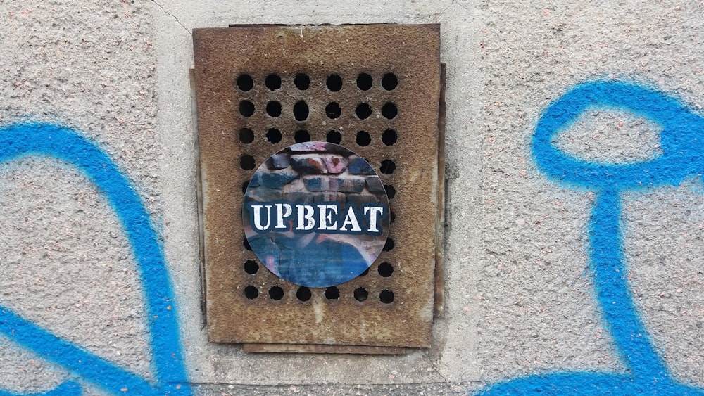 a sign on a wall that says upbeat