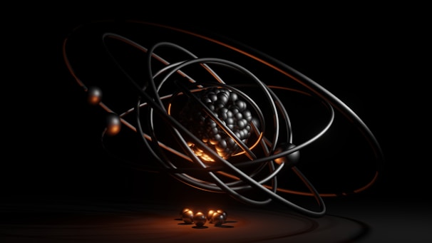 A dark, abstract, and futuristic representation of an atom, featuring a cluster of metallic spheres at the center surrounded by orbiting rings. The orange and black lighting adds a dramatic effect, emphasizing the spherical forms and giving a sense of depth.