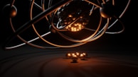 A 3D representation of an atomic structure with orbiting electrons. The nucleus is composed of tightly packed spheres and surrounded by several rings with individual spheres representing electrons. A warm glow illuminates the nucleus, casting shadows and reflections.